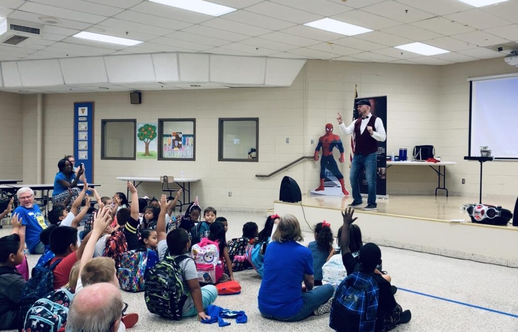 Students seated on the floor watching Matt perform