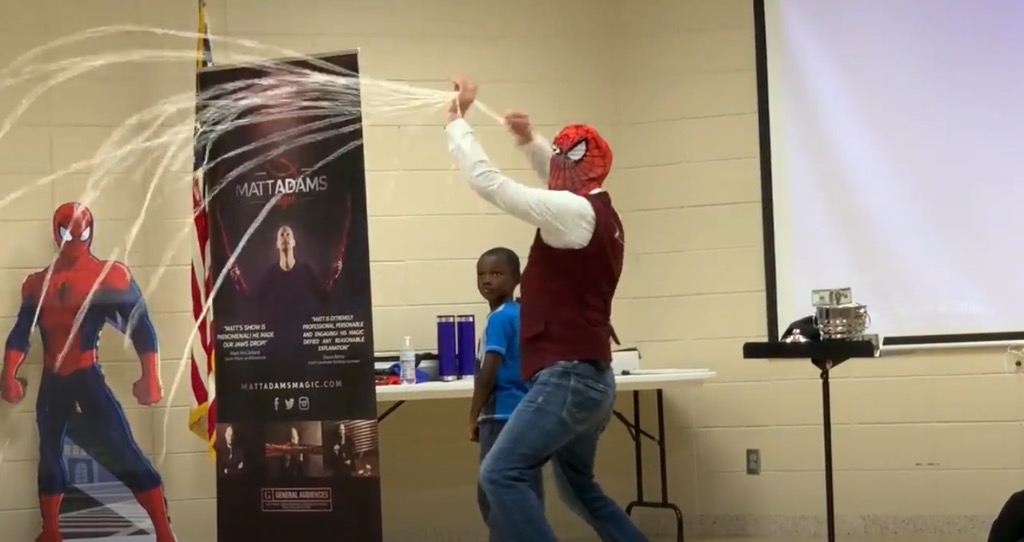 Matt throwing streamers on stage as a student watches