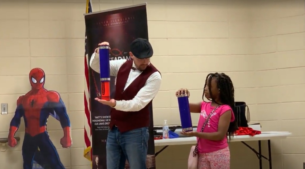 Matt performing with a student volunteer at a school assembly